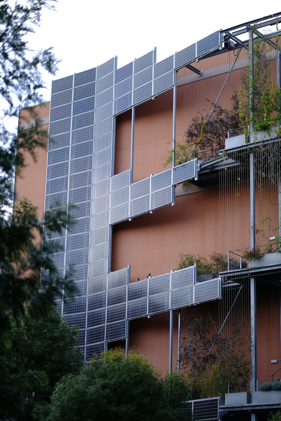 Facciata di un edificio con pannelli solari e giardini verticali.